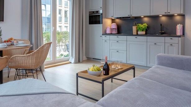 A modern apartment with a dining area, kitchen, and living room.