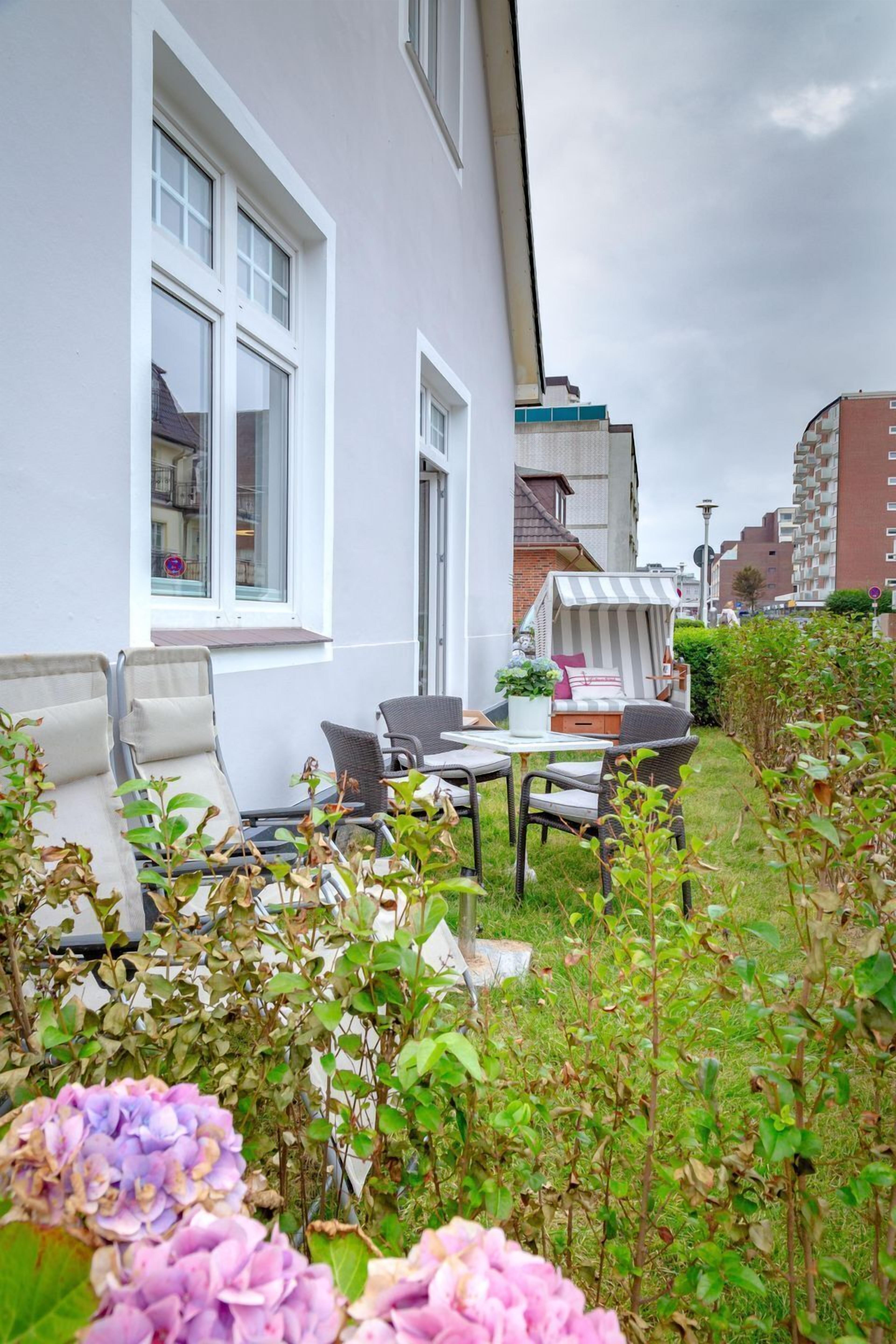 A patio area with outdoor furniture, a striped canopy, and a view of a residential building.
