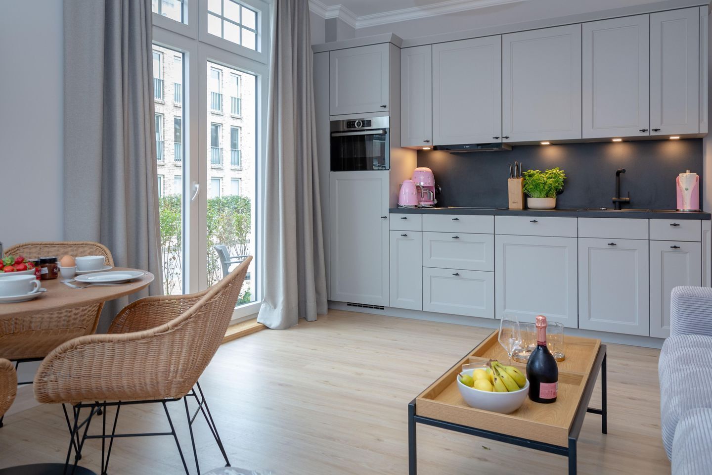 A modern kitchen with white cabinets, a built-in oven, and a coffee machine.