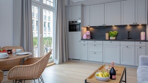 A modern kitchen with white cabinets, a built-in oven, and a coffee machine.