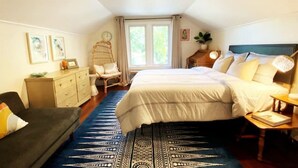 Een slaapkamer met een bed, een dressoir, een stoel en een raam.