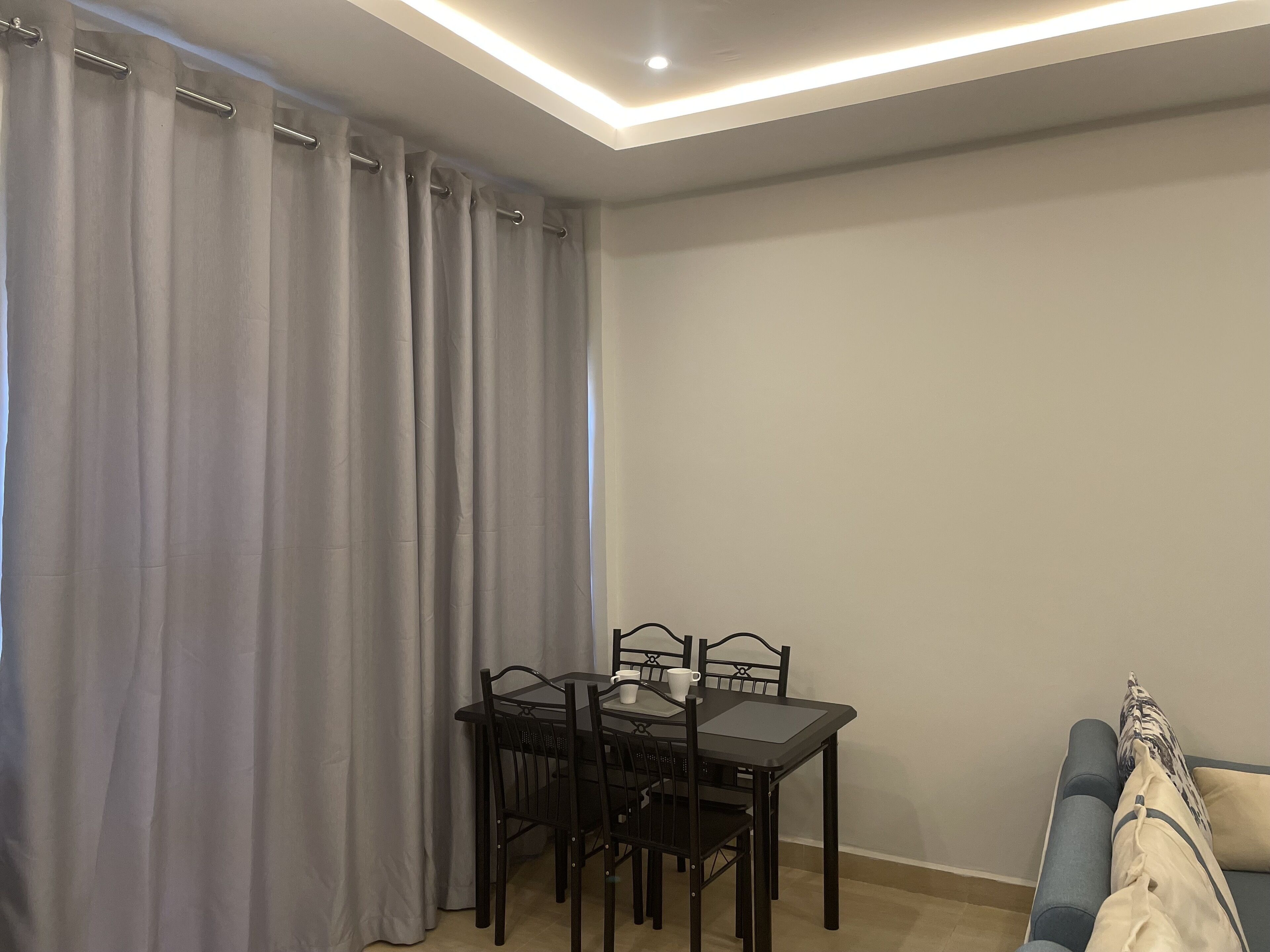 A dining area with a table and chairs, a sofa, and a window with curtains.