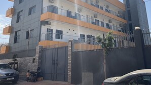 A multi-story building with balconies, a gated entrance, and a parked car. - Seven Heaven Plaza (Brufut)