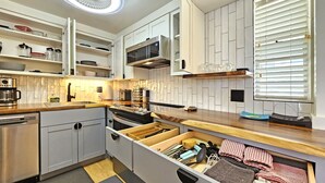 A modern kitchen with white cabinetry, a built-in microwave, and a wooden countertop. - 9th Floor Studio Apt, Full kitchen & Insane views! (Honolulu)