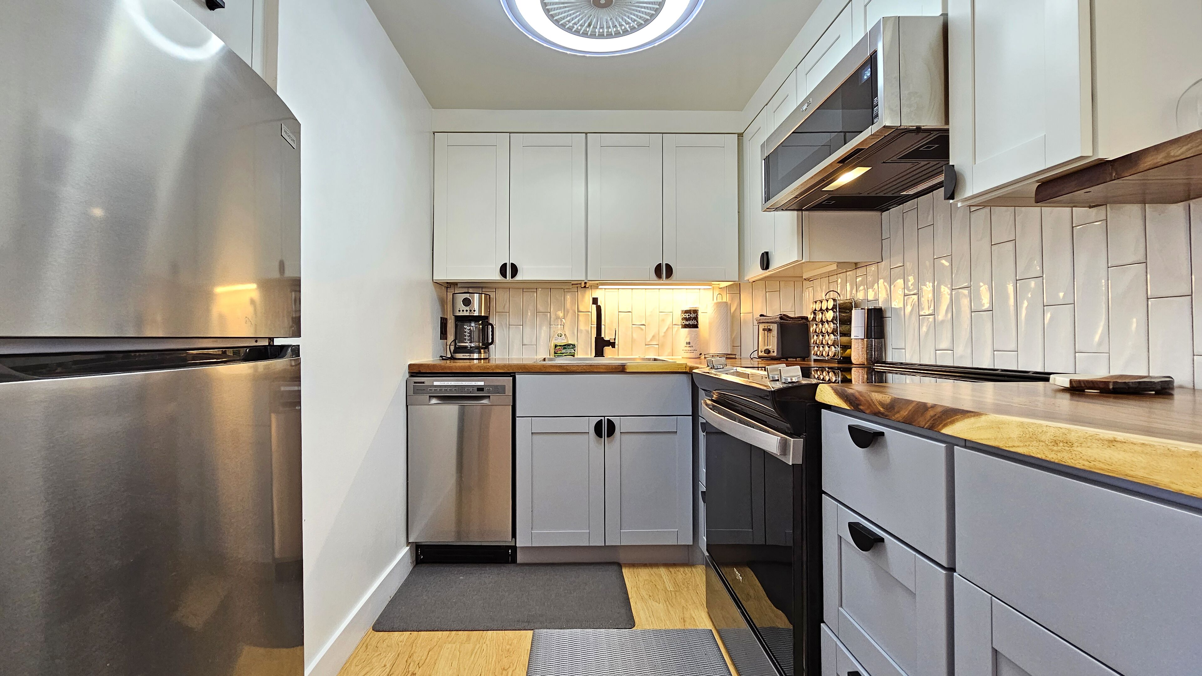 Een moderne keuken met roestvrijstalen apparatuur, witte kasten en een houten aanrecht.
