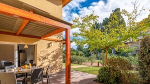 An outdoor patio with a wooden deck, a table with chairs, and a pergola structure. - Cosy apartment for 6 guests with pool, A/C, WIFI, TV, terrace and pets allowed (Porto-vecchio)