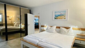 Une chambre d’hôtel moderne avec un grand lit, des tables de chevet, un miroir et un tableau au mur.
