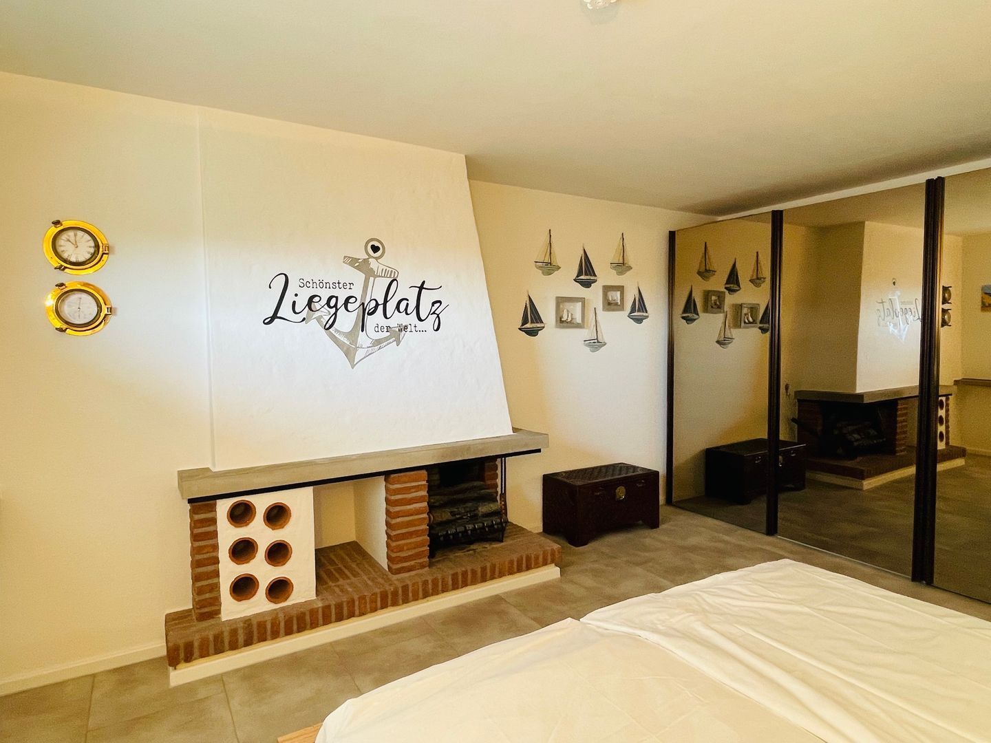 Ein Schlafzimmer mit Kamin, einem Bett, einem Spiegel und dekorativen Wandbildern.