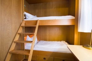 Ein Etagenbett mit einer Leiter, Holzwänden und einem kleinen Schreibtisch mit Lampe.