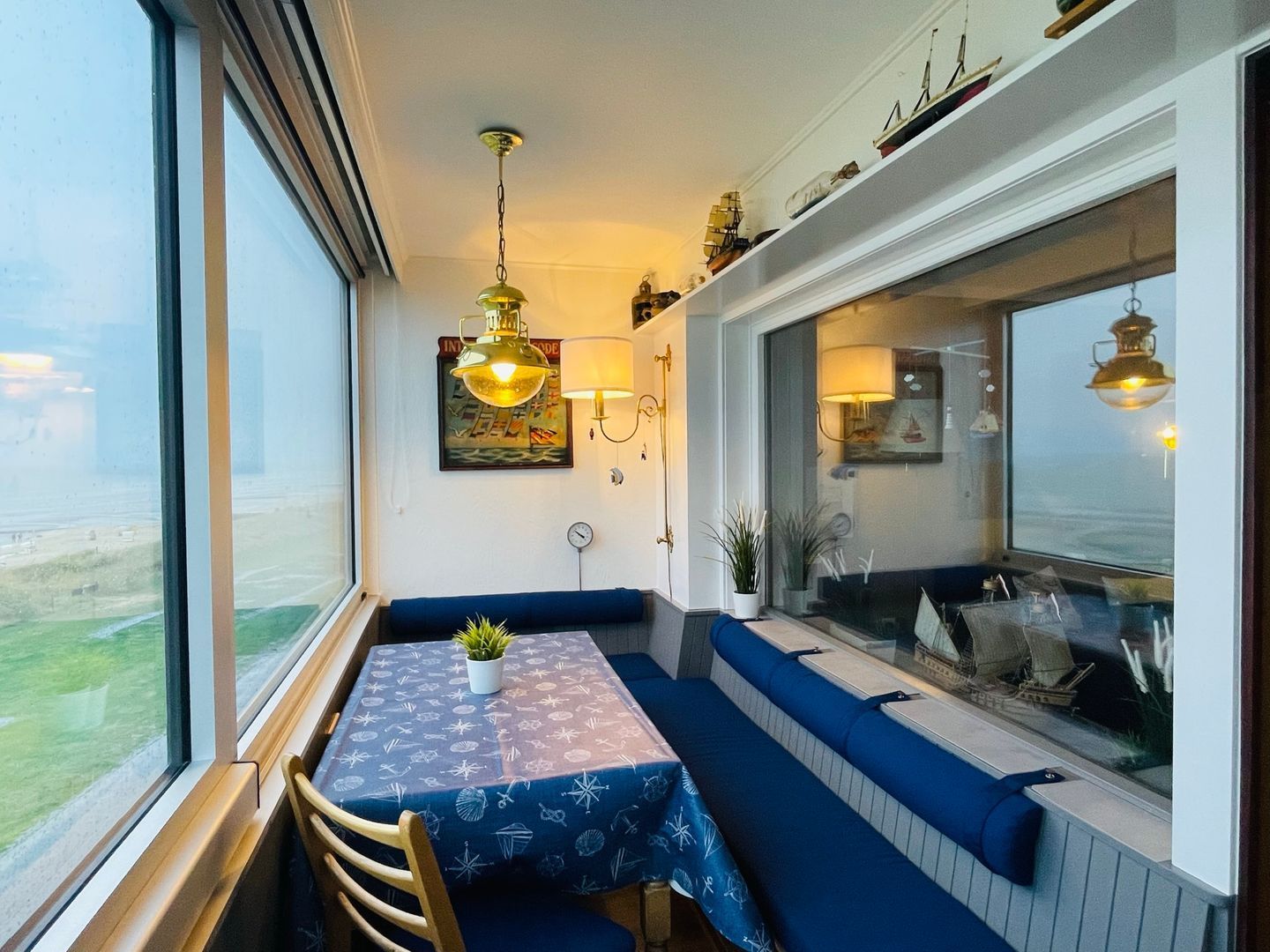 Ein Essbereich mit Tisch und Bänken, einer Hängeleuchte und Blick durch ein Fenster.