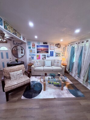A living room with a sofa, armchair, coffee table, and various wall decorations. - Good Location / Good people AND GOOD VIBES ONLY  (Spring Hill)