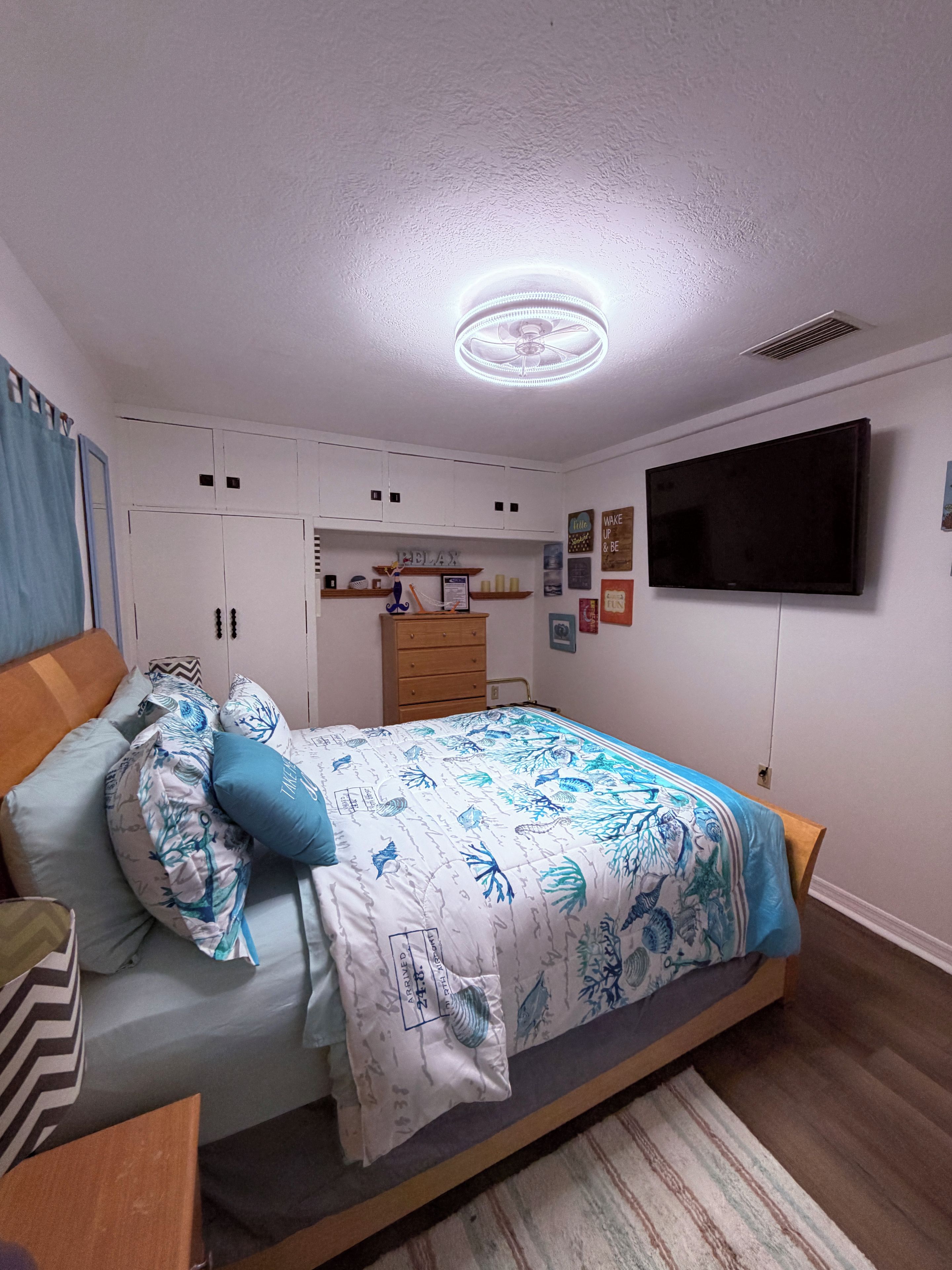 A bedroom with a bed, a TV, a wardrobe, and a desk.