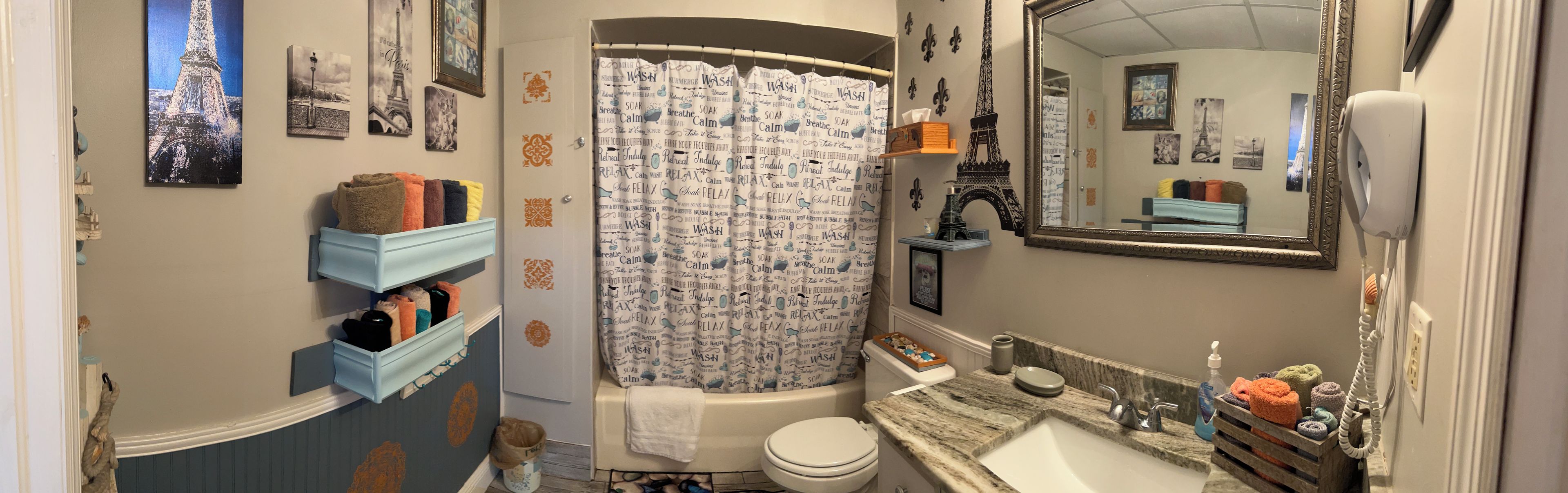 Un baño con bañera, inodoro y lavamanos. Hay toallas y artículos de aseo en el mostrador.
