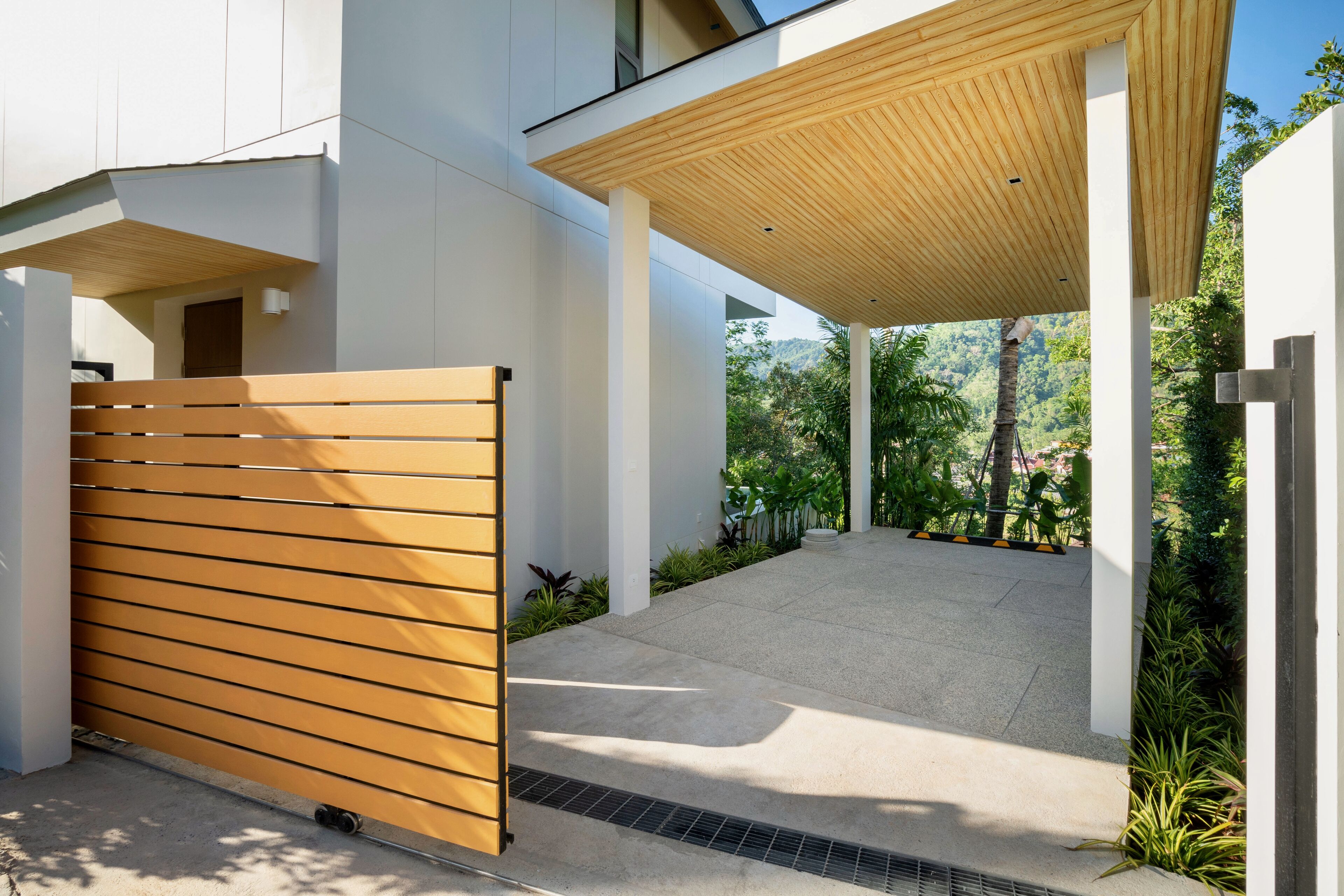 A modern outdoor area with a wooden fence, concrete steps, and a covered walkway.