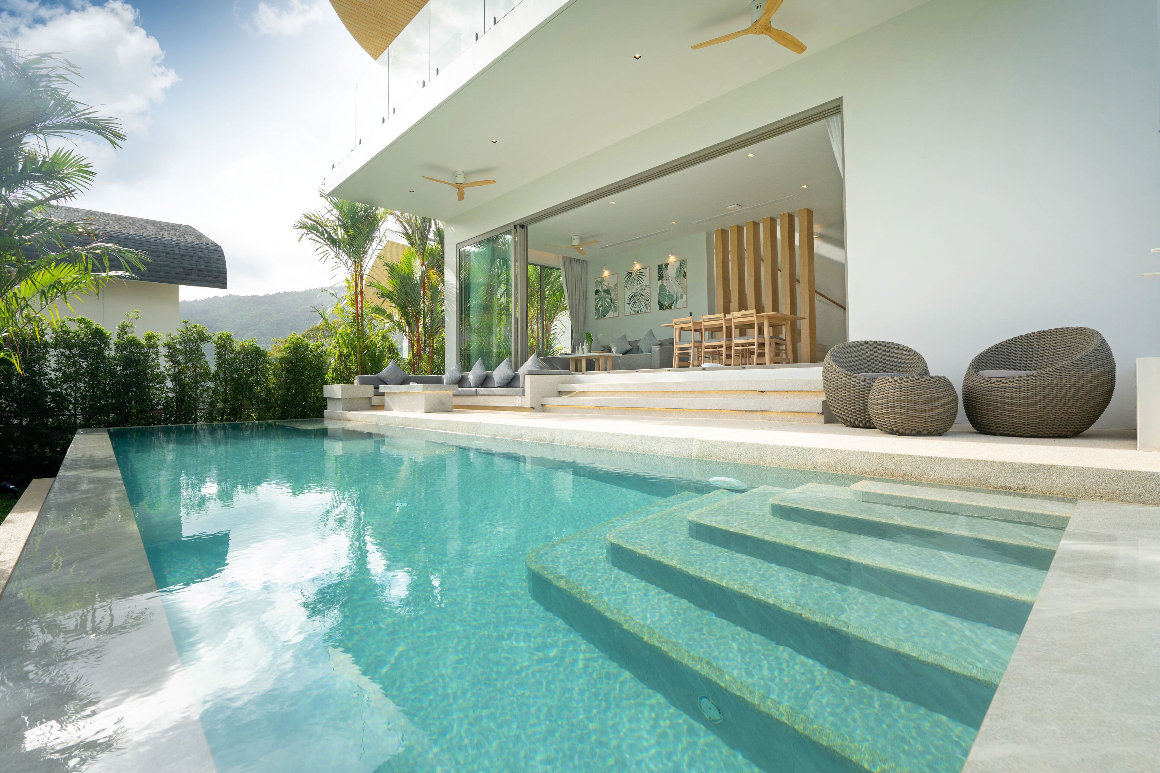 A modern poolside area with a clear pool, steps leading into the pool, and outdoor seating.