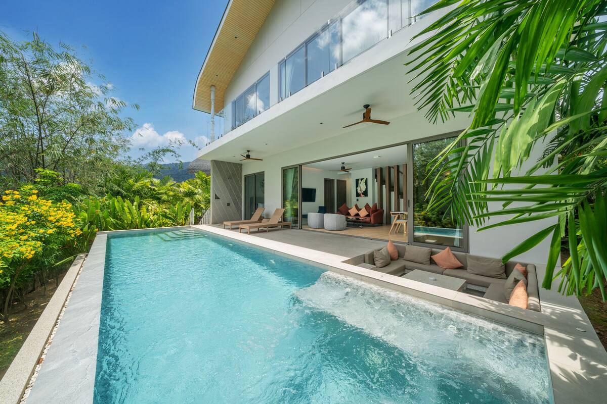 Une maison moderne dotée d’une piscine, d’un espace salon extérieur et d’une végétation luxuriante.