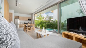 A modern living room with a sofa, a dining area, and a kitchen. - Himmapana Villas - Hills  (Kamala)