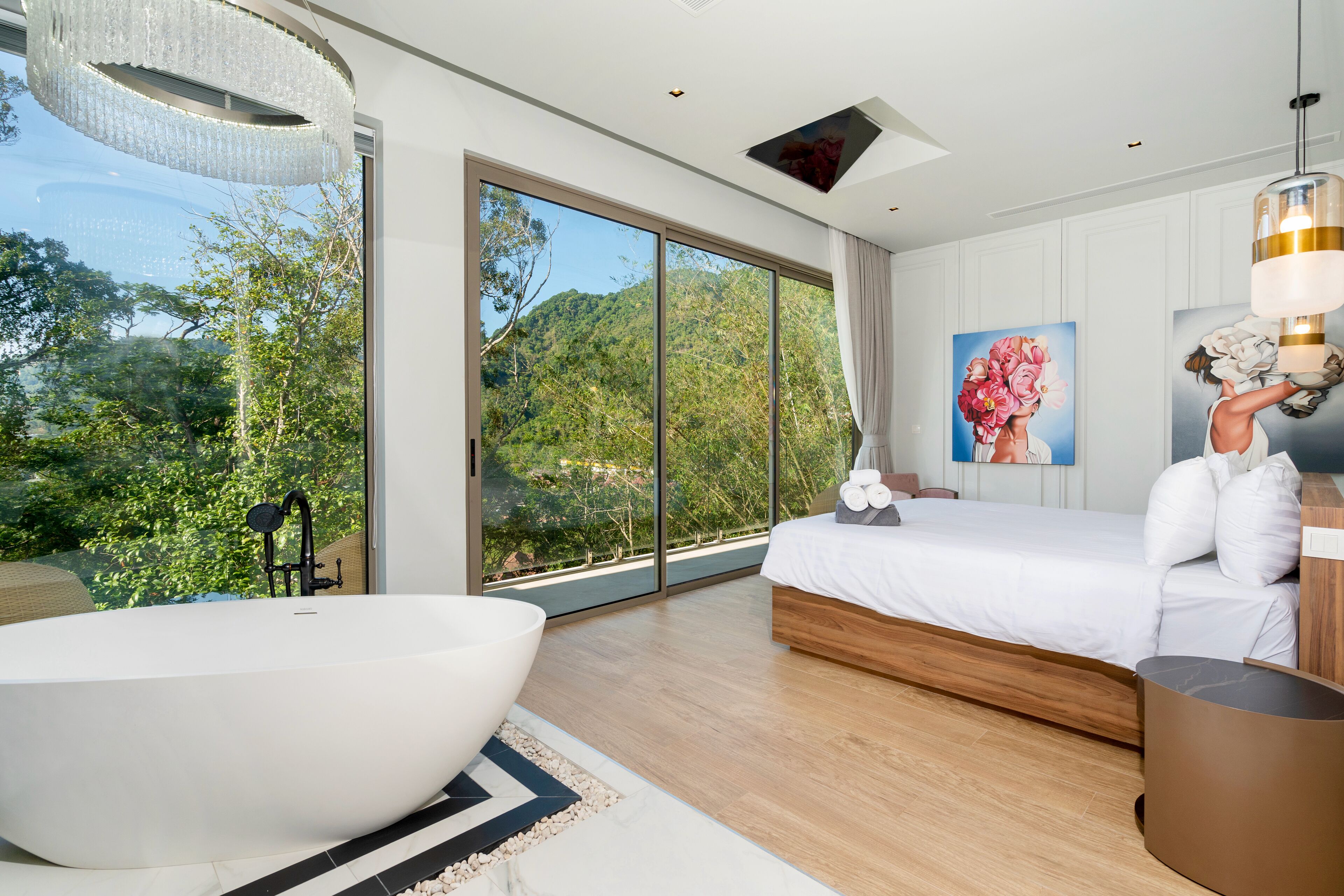 Un dormitorio moderno con una cama grande, una bañera y vistas a un bosque.