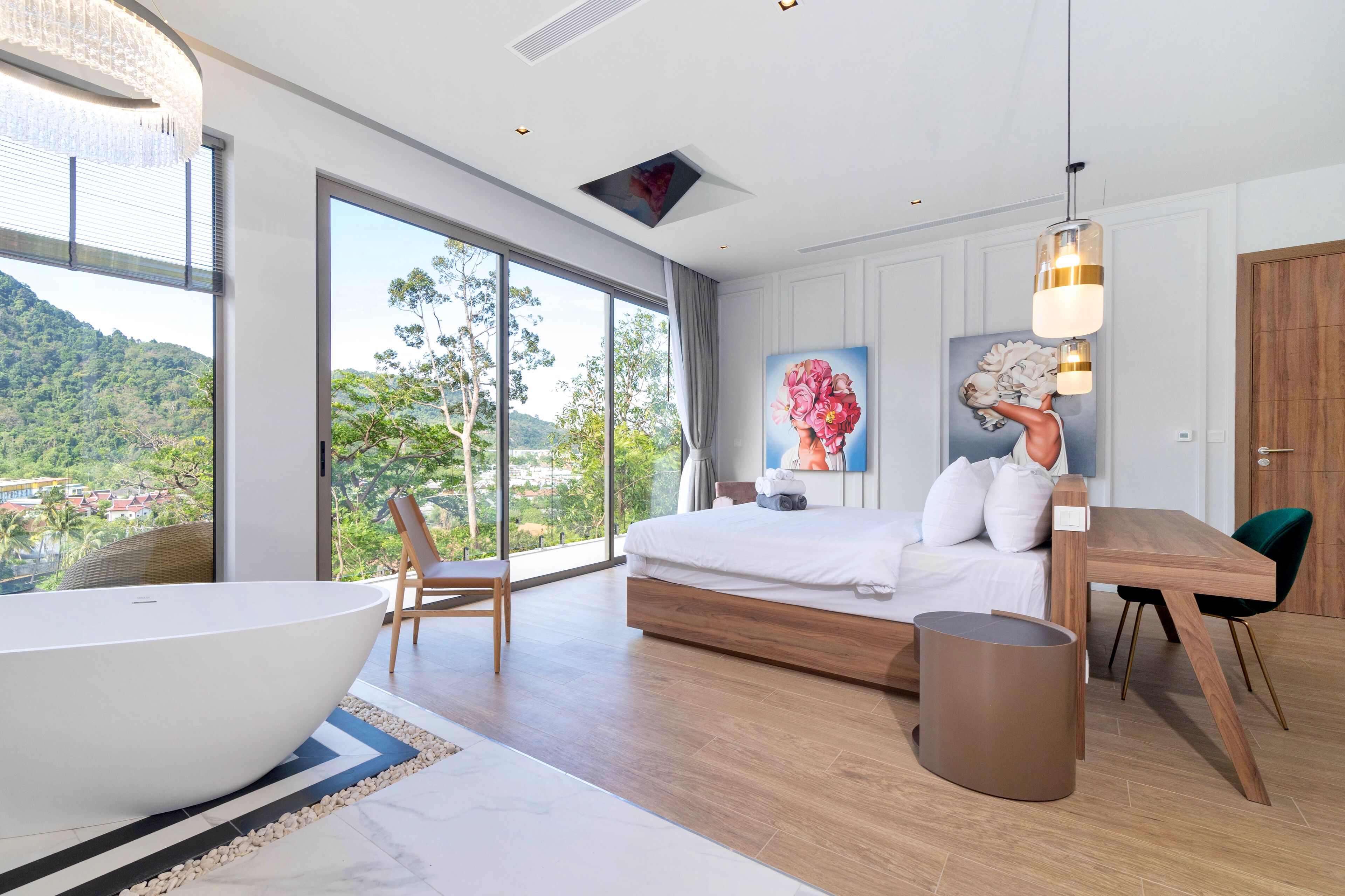 A modern bedroom with a large window, a bathtub, a wooden bed, a dining table, and a view of a green landscape.