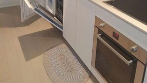 Una cuina compacta amb microones integrada, cafetera i un rentaplat.