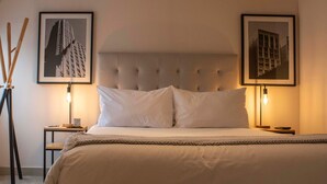 A neatly arranged bedroom with a large bed, two bedside tables, and two framed pictures on the walls. - Espacio Luxury- Edificio Pedro de Osma (Lima)
