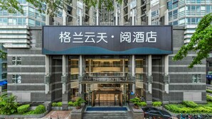 Ein Hotel Eingang mit einer großen Schrifttafel in chinesischen Schriftzeichen, einer Glasfassade und einem Parkplatz für Motorräder.