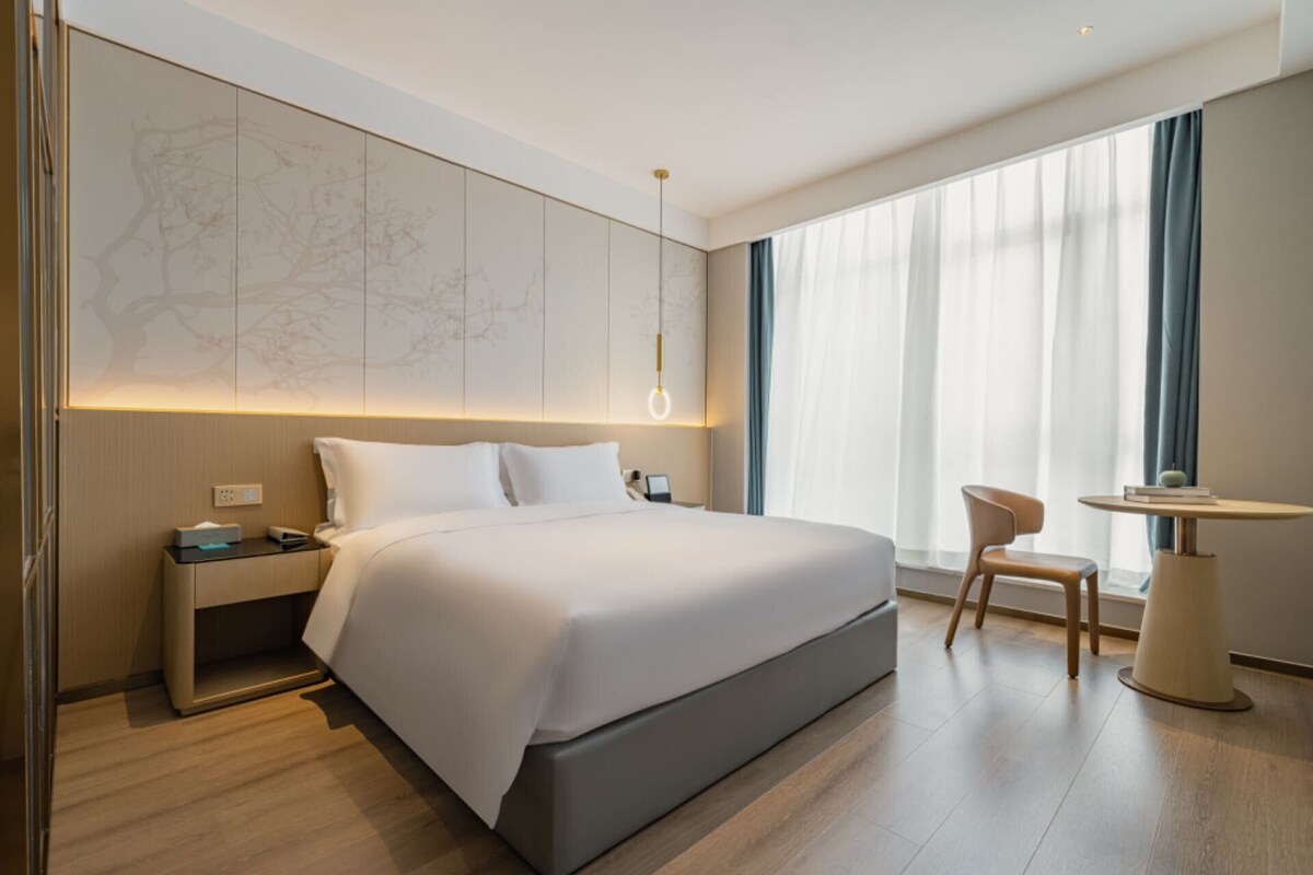 Ein modernes Hotelzimmer mit einem großen Bett, einem Schreibtisch und einem Stuhl.