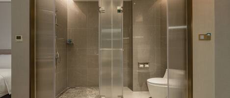 Une salle de bain moderne avec une douche à parois de verre, des toilettes et un lit dans la pièce adjacente.