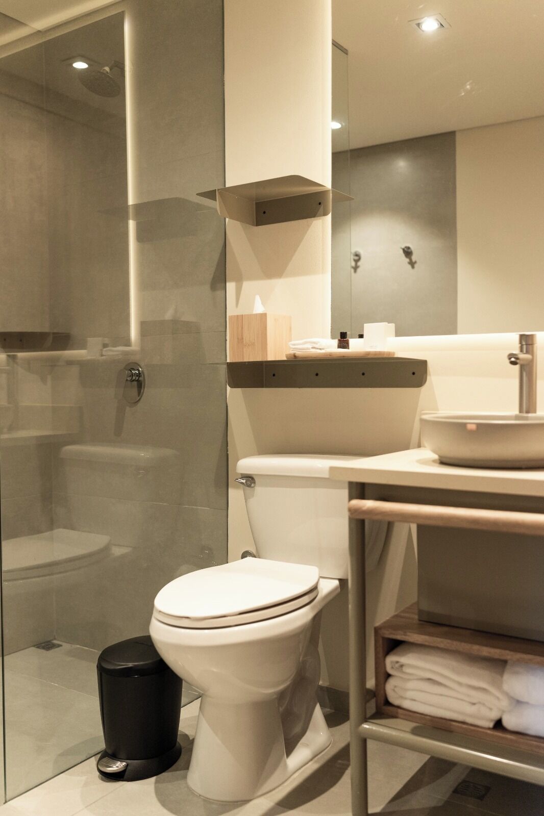 Un baño moderno con cabina de ducha de vidrio, inodoro, lavamanos y toallero.