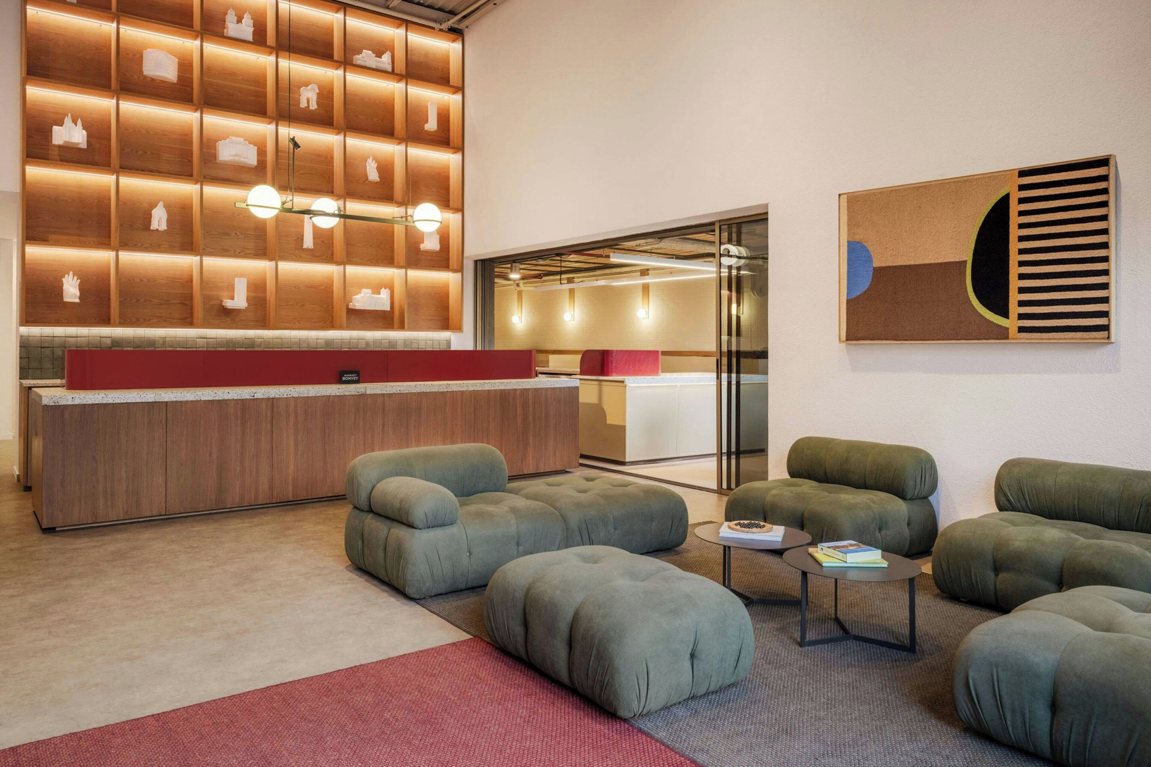 A modern lobby with a reception desk, seating area, and a wall with illuminated shelves.