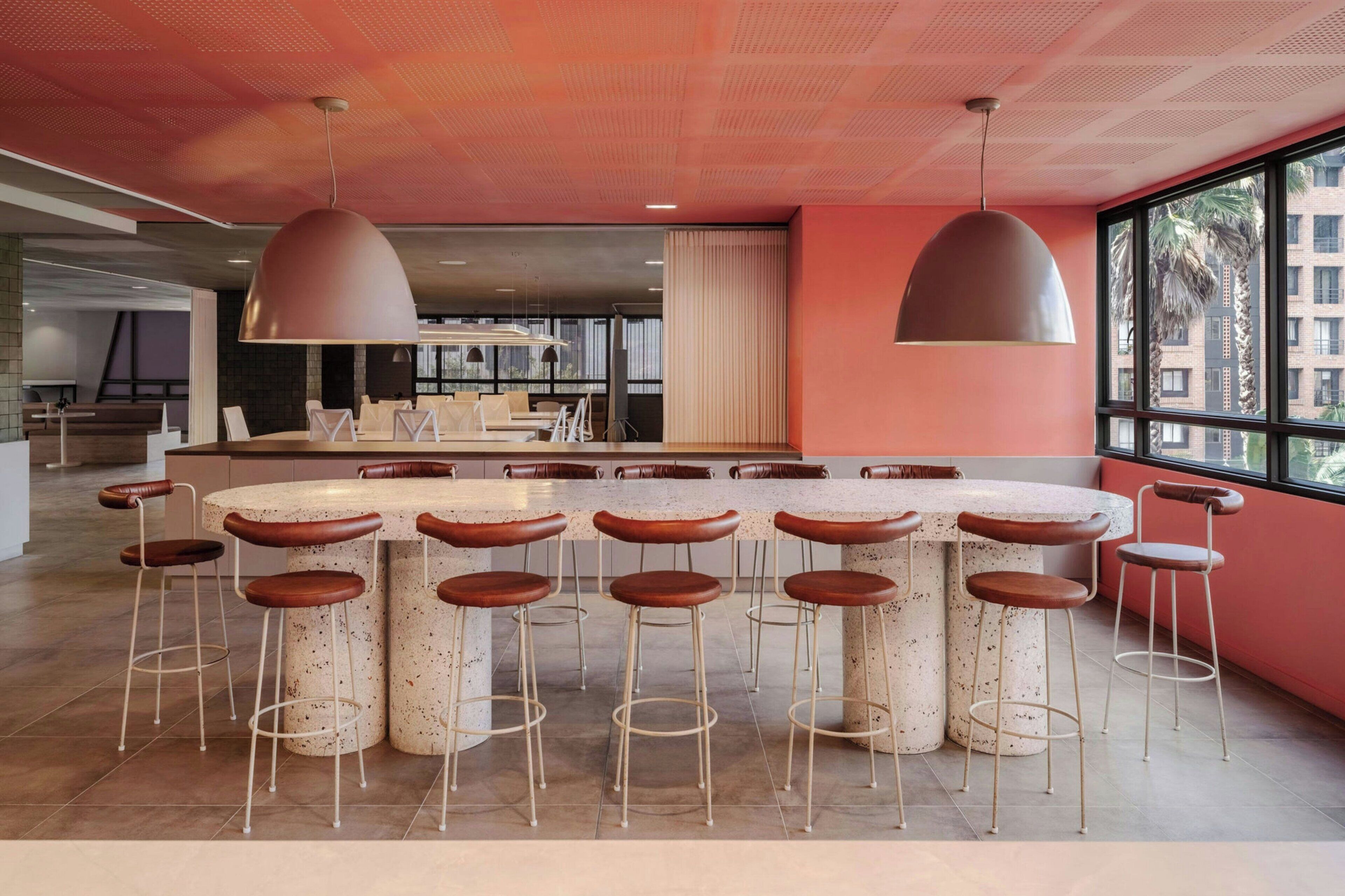 A modern kitchen with a central island, bar stools, and pendant lighting.