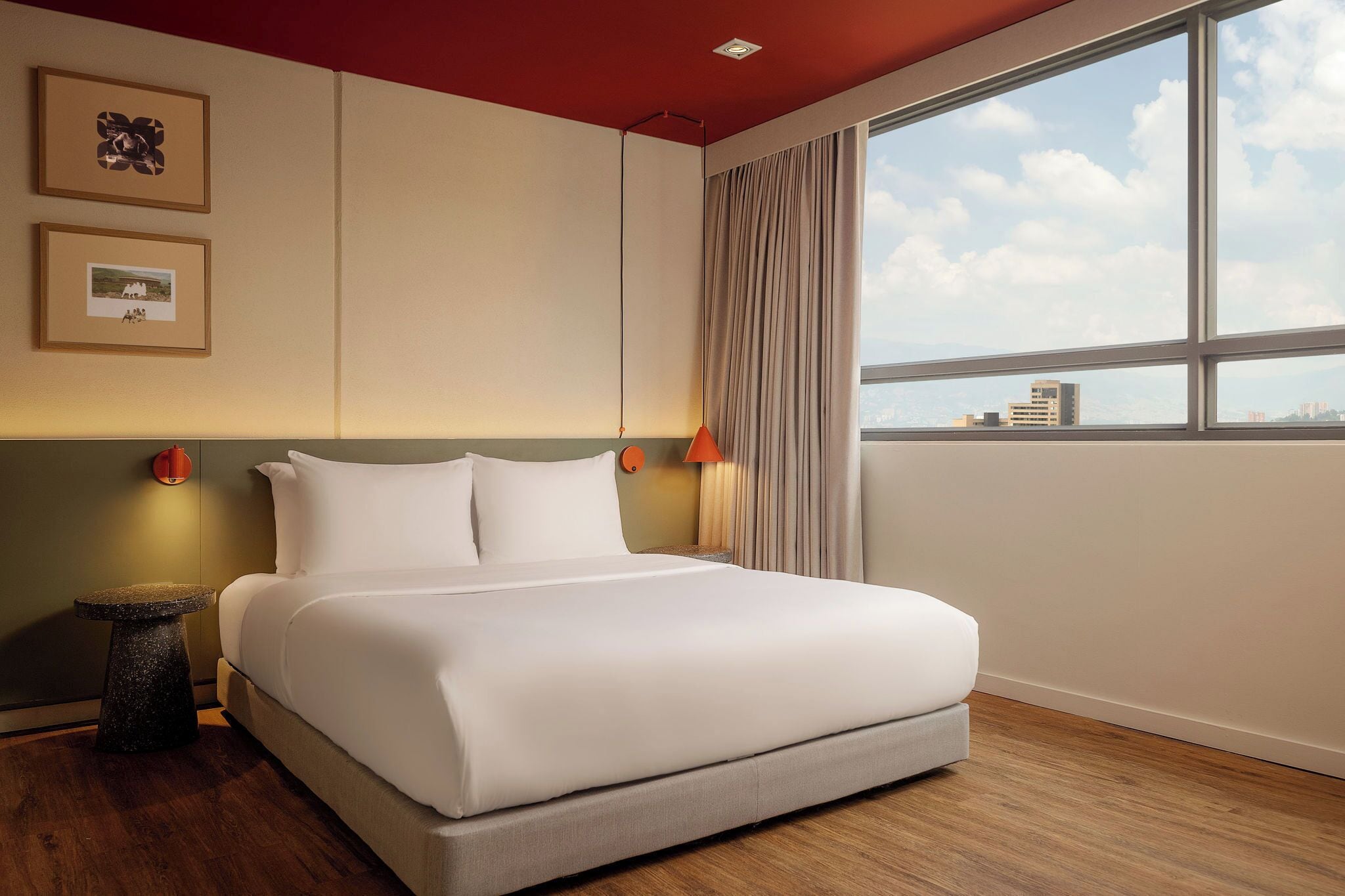 Una camera d'albergo con un grande letto, un comodino, una lampada e una finestra vista città.