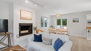 A living room with a fireplace, a television, and a dining area with a view of the outdoors. - Walk to Newport, 1st & 2nd Beaches, & Cliff Walk from this Newly Redone Home (Middletown)
