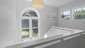 A room with a large arched window, a white bench, and a hanging light fixture. - Walk to Newport, 1st & 2nd Beaches, & Cliff Walk from this Newly Redone Home (Middletown)