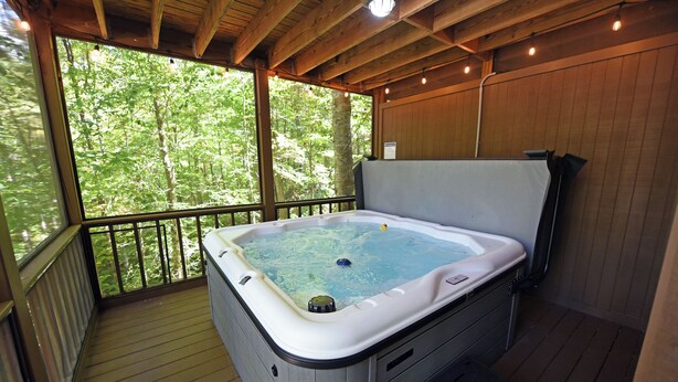 Un jacuzzi en una terraza de madera con vista a un bosque.