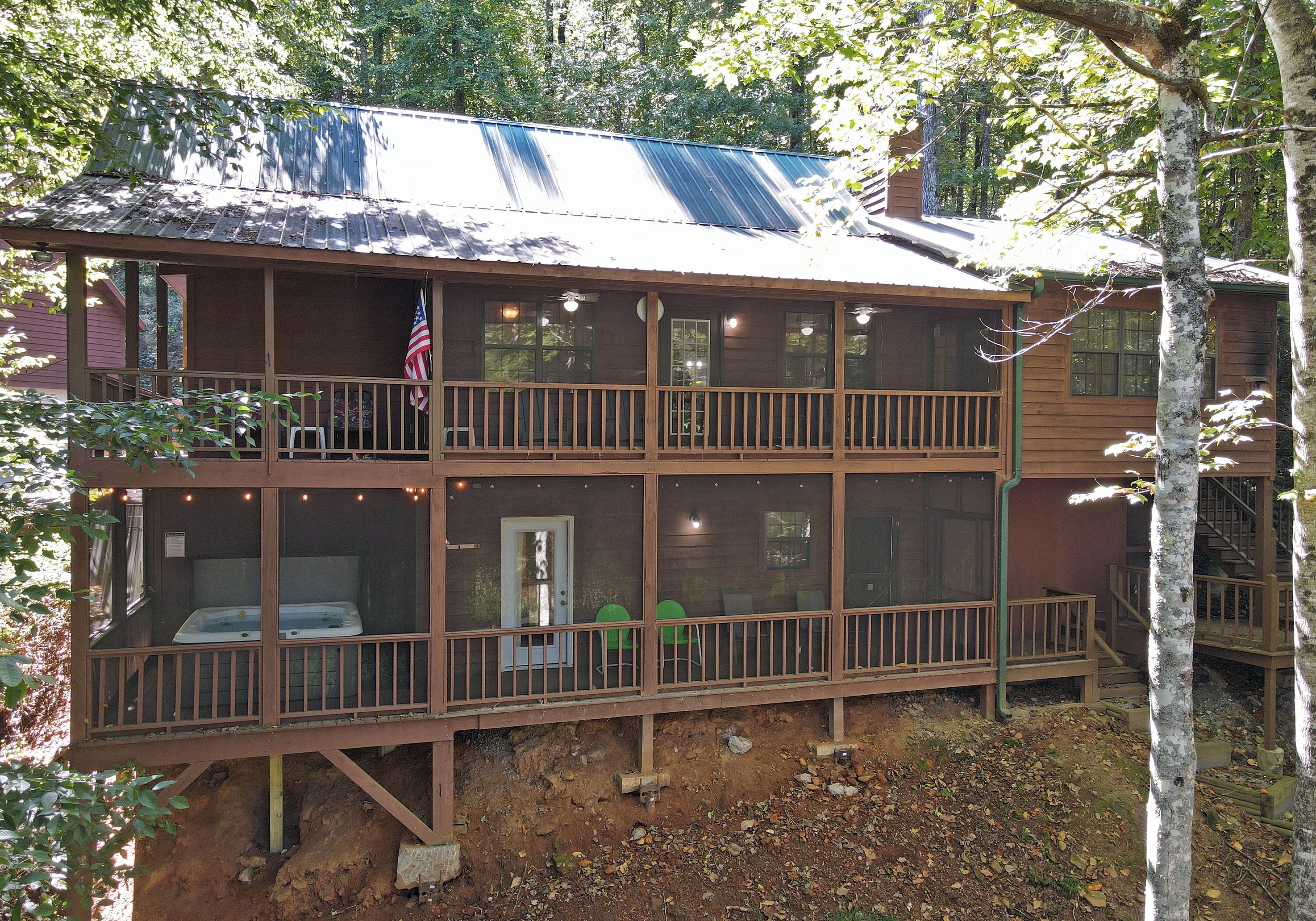 Eine zweistöckige Hütte mit Balkon, Whirlpool und Terrasse.