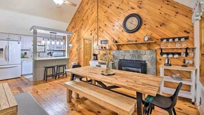 Una cocina acogedora con paredes de madera, una chimenea de piedra y un comedor con una mesa y bancos de madera.