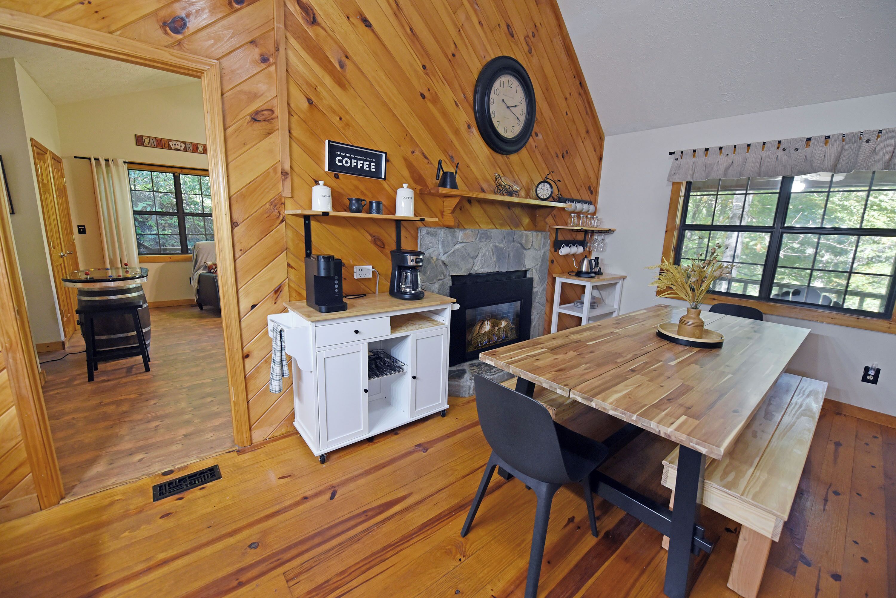A cozy wooden interior with a coffee station, a fireplace, and a dining area.