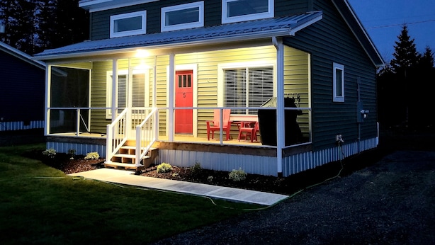 A two-story house with a porch, a red door, and a small deck area. - #5 Scenic Aspy Mountain Cottage, Margaree River access, near Cabot Trail (Margaree Valley)
