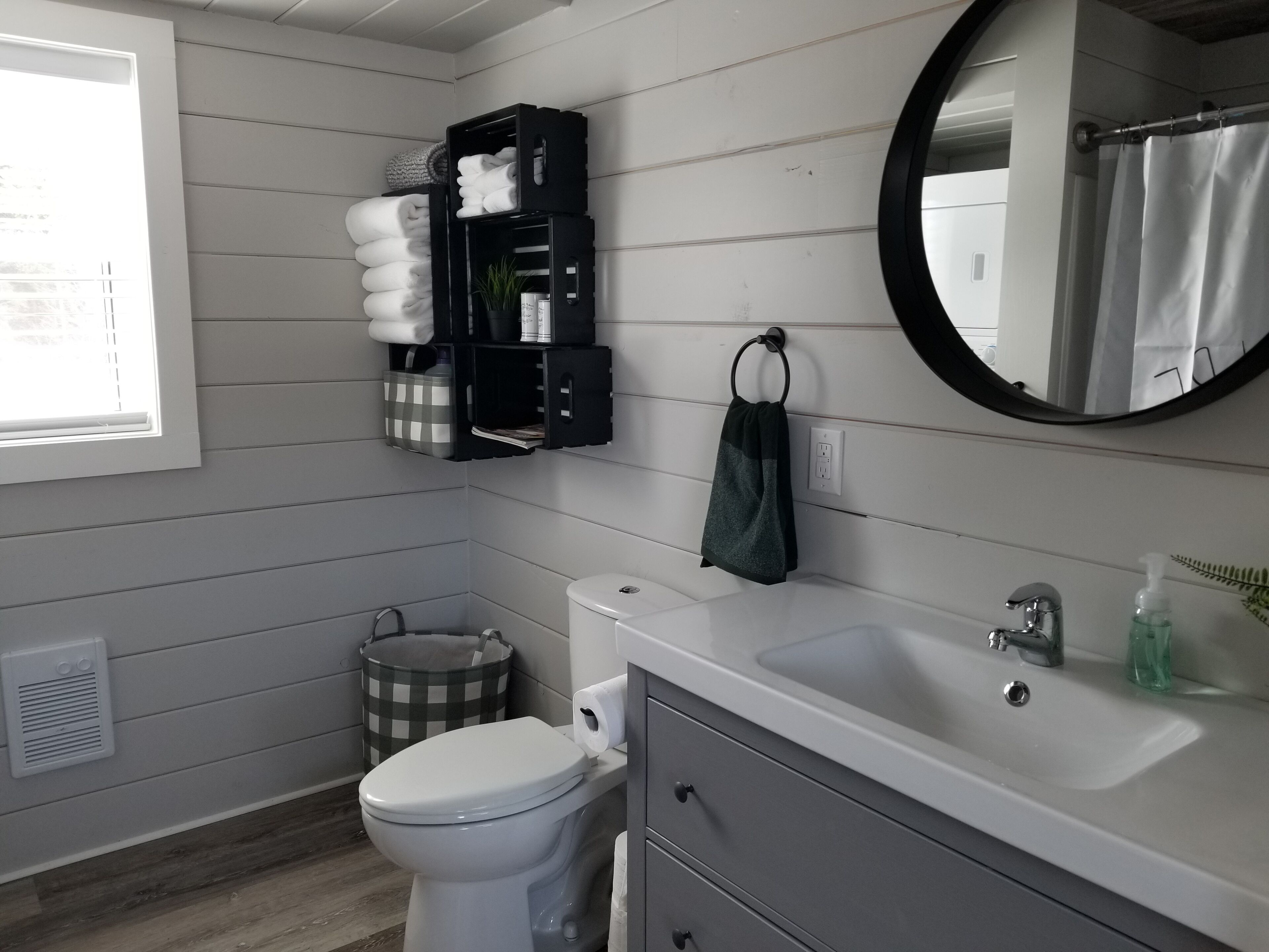 A bathroom with a toilet, sink, and storage shelves.