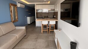 Una sala de estar moderna con un sofá, un comedor con una mesa y sillas, y una cocina con microondas y armarios.