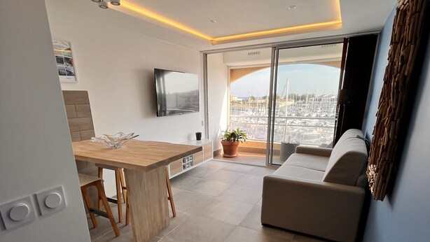 Una sala de estar moderna con un televisor de pantalla plana, un comedor con mesa de madera y un sofá.
