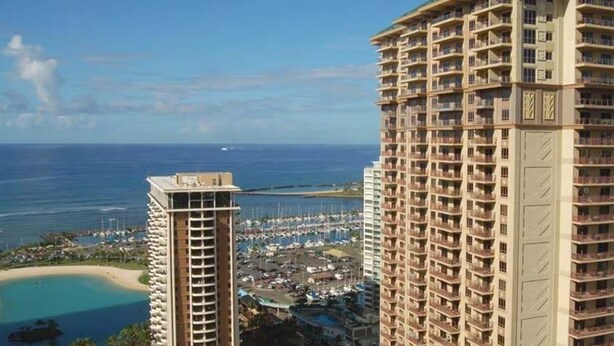 A high-rise hotel with multiple balconies, a marina with boats, and a beach in the background. - Grand Waikikian 1BR Partial Oceanview Villa (Kapolei)