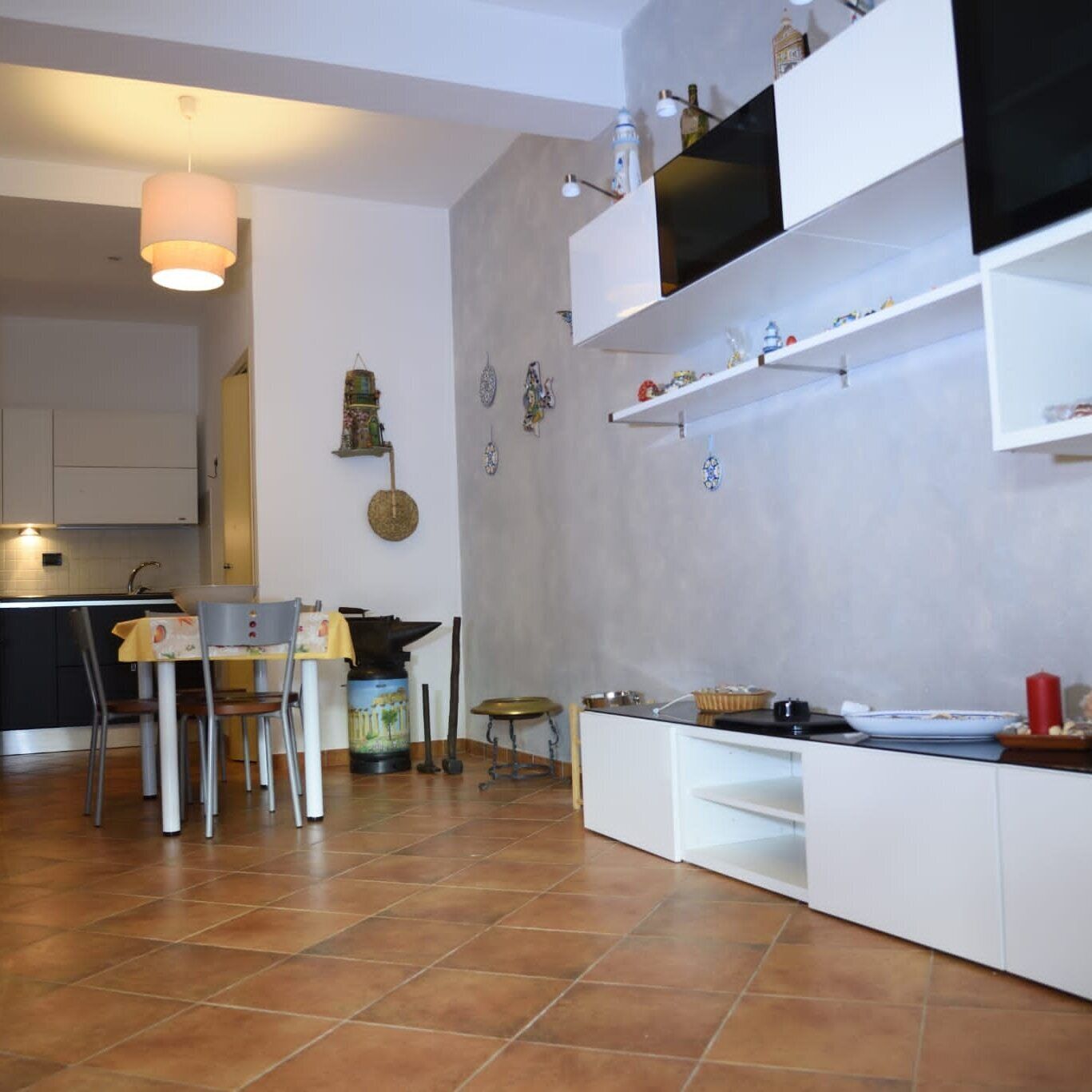 Une cuisine moderne avec des meubles blancs, un coin repas comprenant une table et des chaises, et un luminaire suspendu.