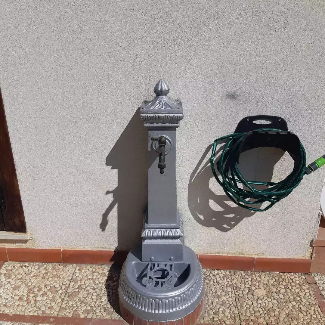 A water fountain with a spout and a hose coiled nearby.