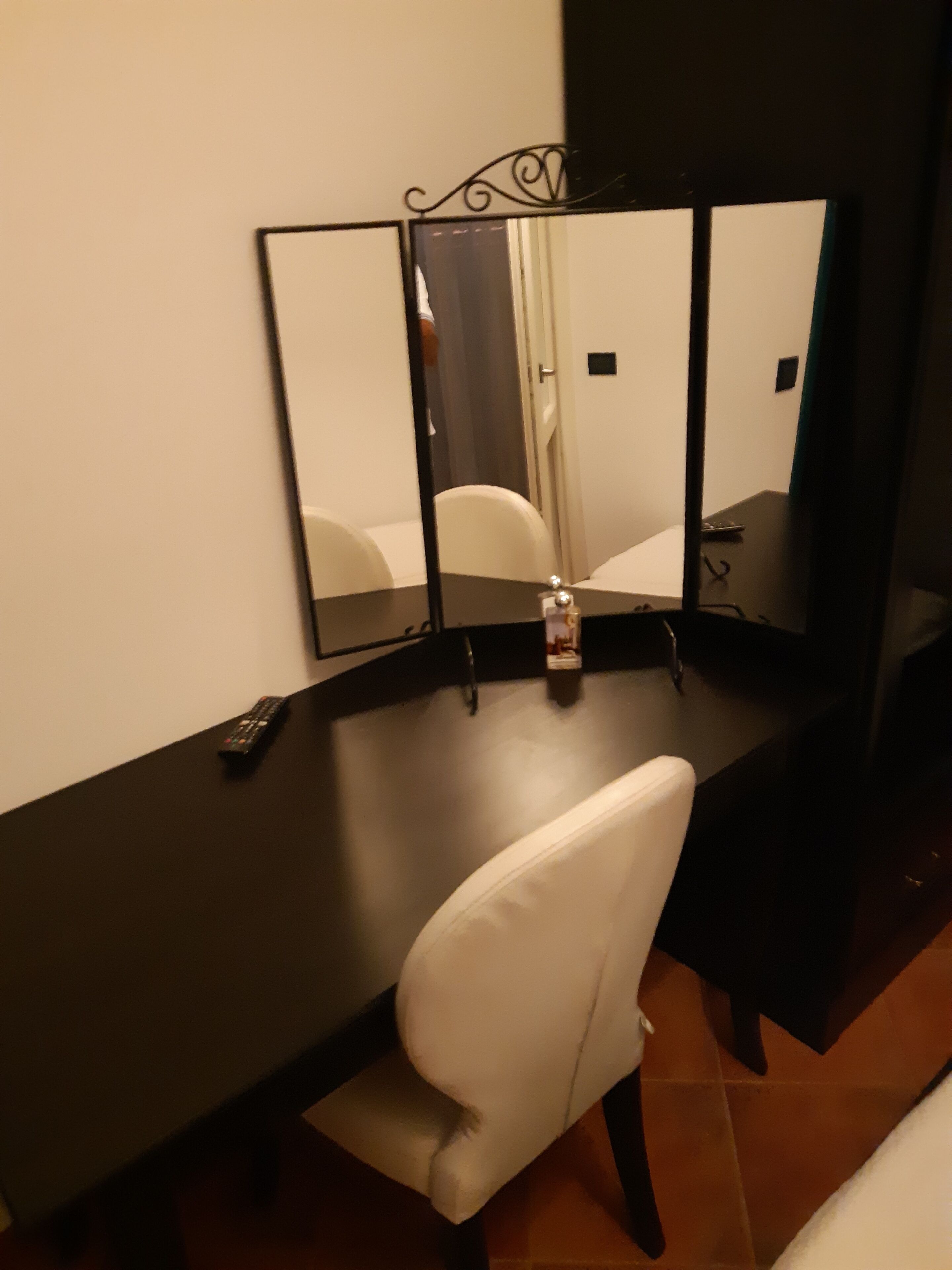 Ein Hotelzimmer mit Schreibtisch, Stuhl und einem großen Spiegel.