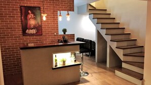 A modern kitchen with a brick wall, a bar area, and a staircase. - Studio 112 - Stay in Style, Stay Central (Ensenada)
