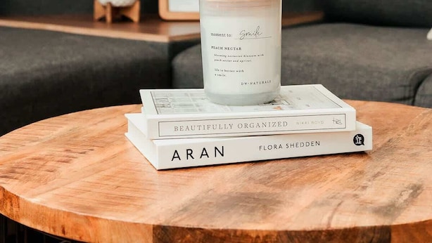 A round wooden table with a white candle and two books on it. - Studio 112 - Stay in Style, Stay Central (Ensenada)