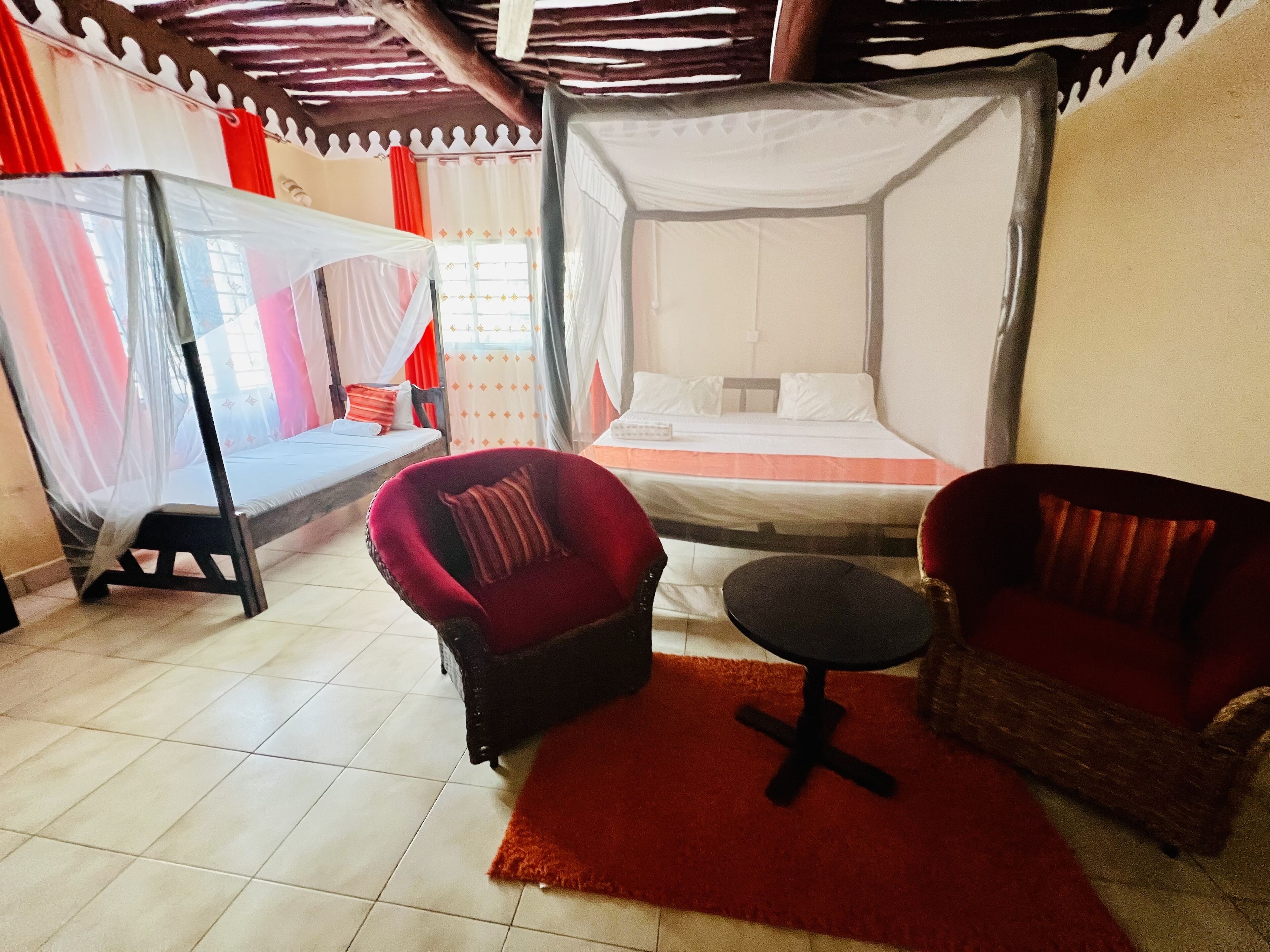 Een kamer met een bed, twee stoelen, een klein tafeltje en een hemelbed.