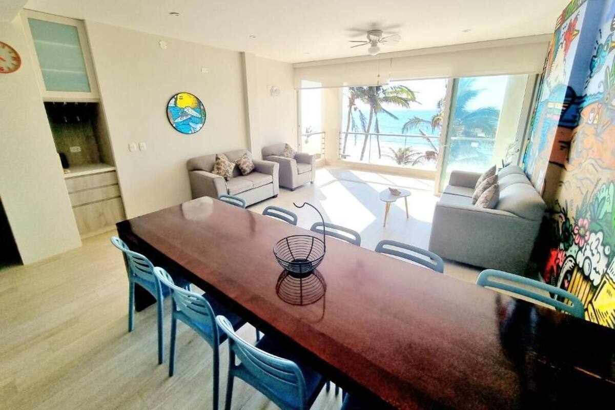A modern living room with a dining area, large windows, and a view of the ocean.